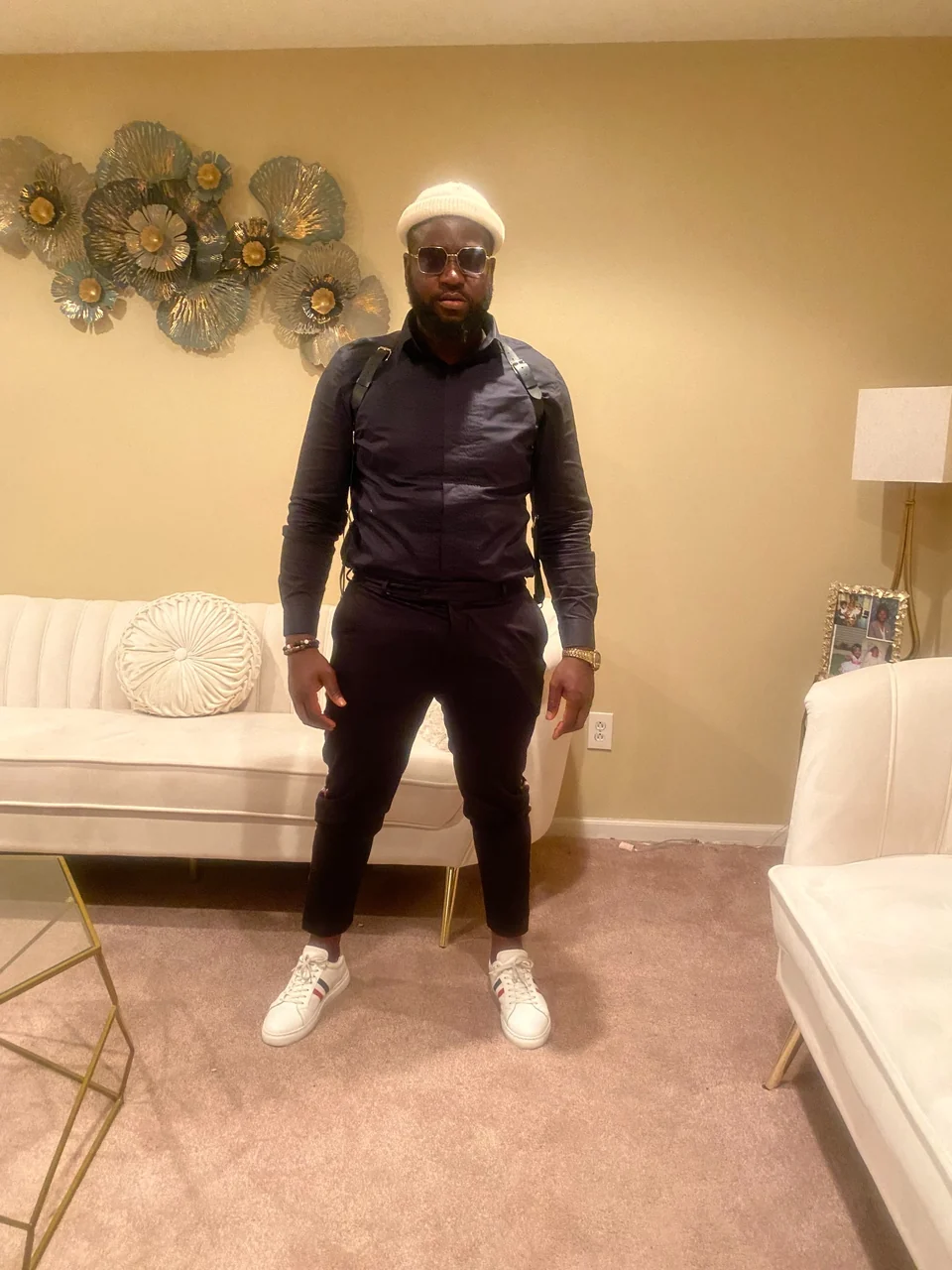 Massayan Sorsor standing in a dark outfit, cream knit cap, and white sneakers